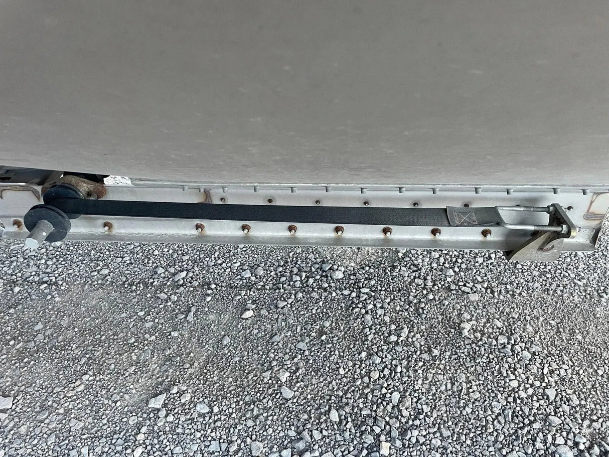 Close-up of a metal trailer latch and lock on gravel ground