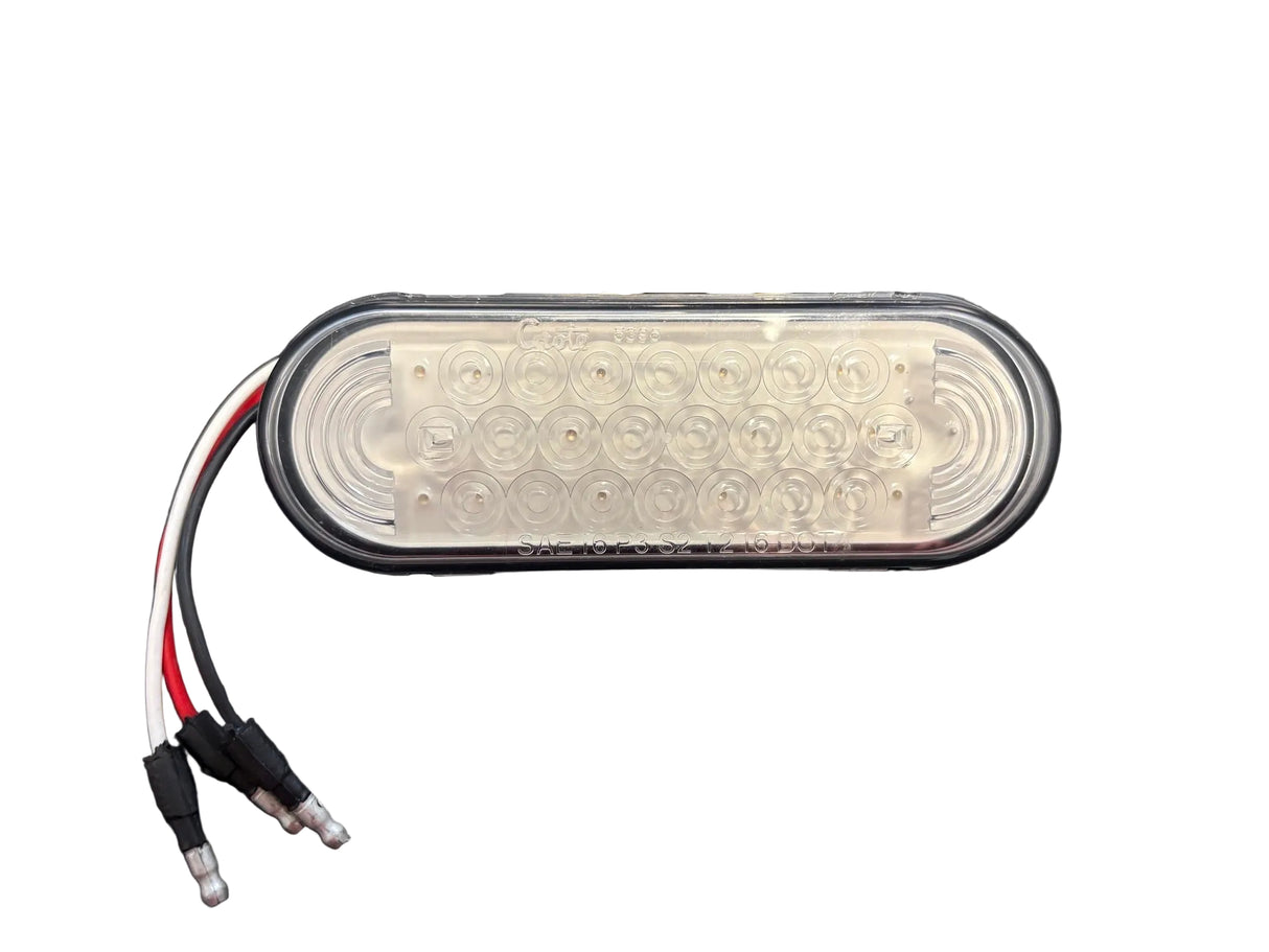 An oval Grote LED marker light with a clear lens and attached wiring