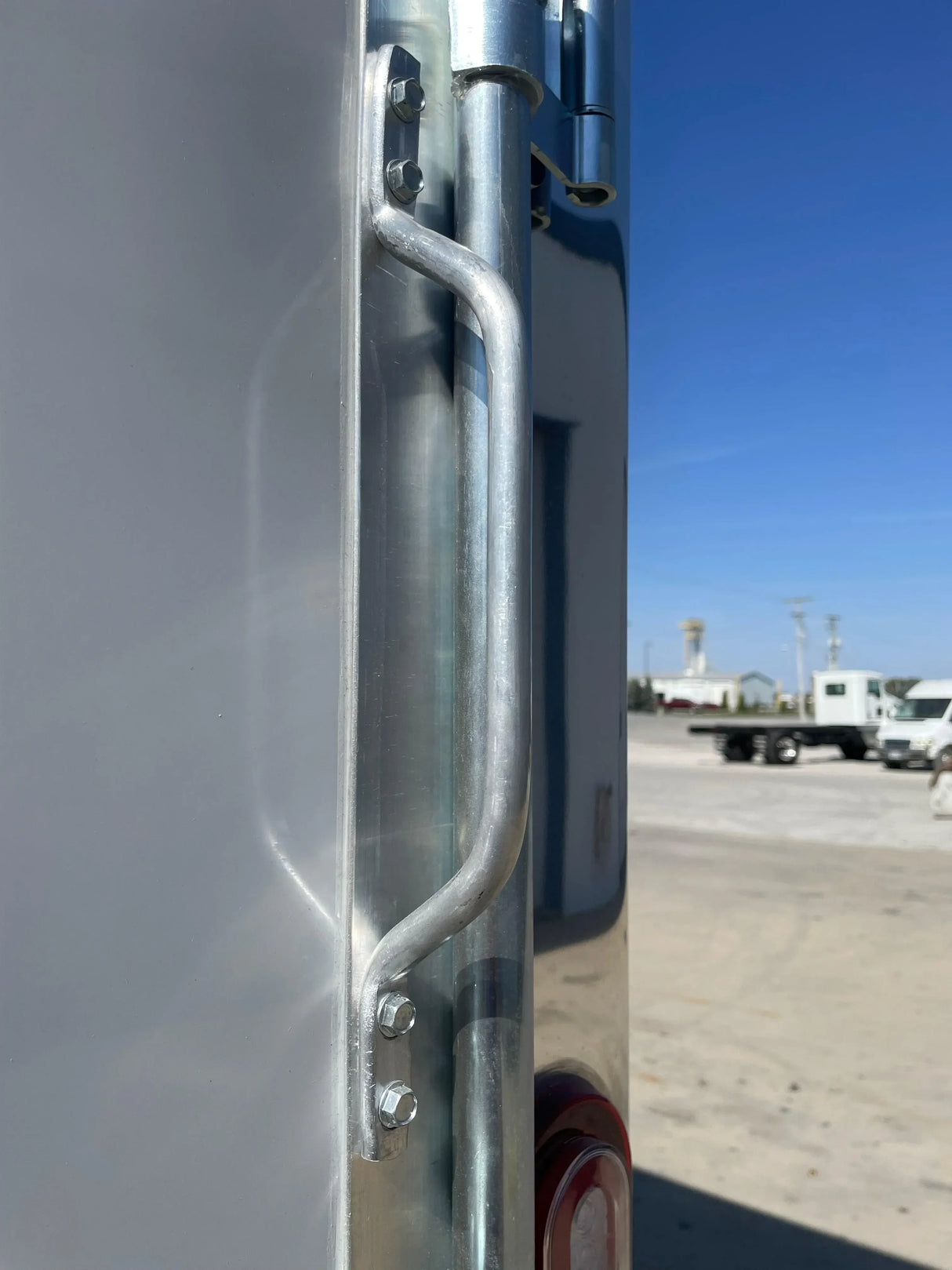 Close-up of galvanized steel trailer door latch with bolts, outdoor lot, blue sky