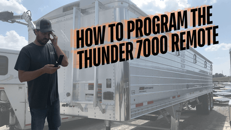 Man using Thunder 7000 remote by aluminum grain trailer, with programming guide text overlay