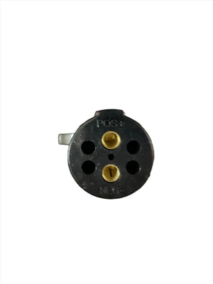Close-up of a round black electrical connector plug with gold contacts on white background