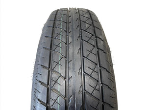 Close-up view of a new black trailer tire with visible tread pattern on white background