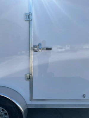 White enclosed trailer side door with metal hinges and latch in sunlight