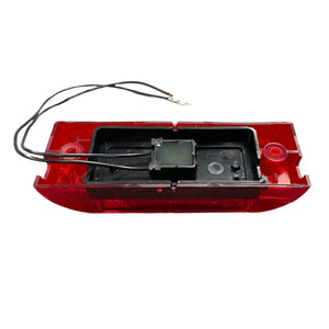 Red automotive LED tail light with exposed wiring on white background