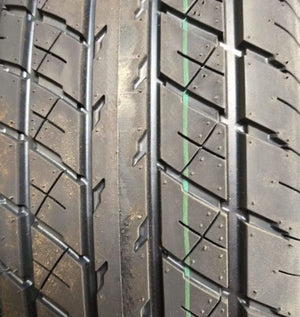 Close-up of car tire tread pattern with black rubber and green guideline