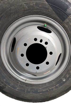 Close-up of a black tire with silver steel wheel rim and green tire valve cap